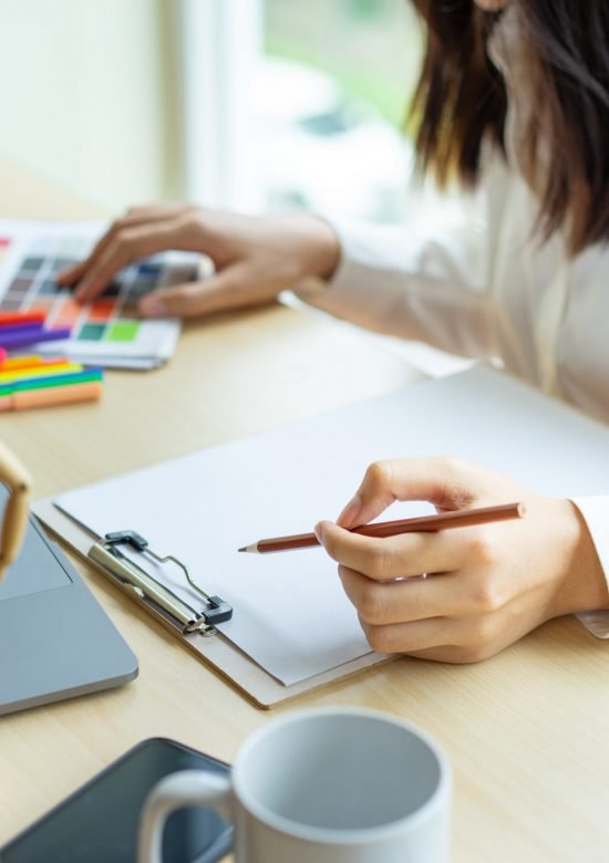 Young woman designer working with color samples for selection on office desk, Architects choosing color samples for design project,Color swatch samples,creative graphic design working desktop.